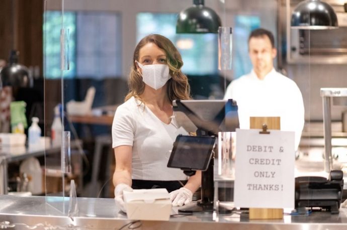 woman wearing mask accepting cashless payment